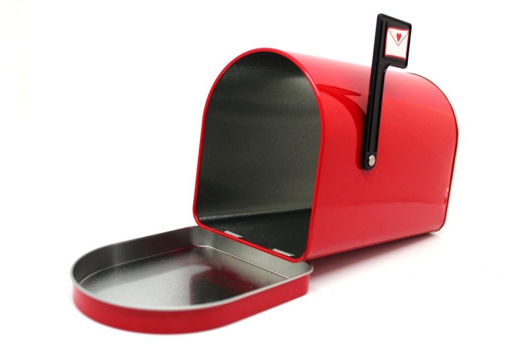 A red mailbox, open, with a little black flag sticking up on it.
