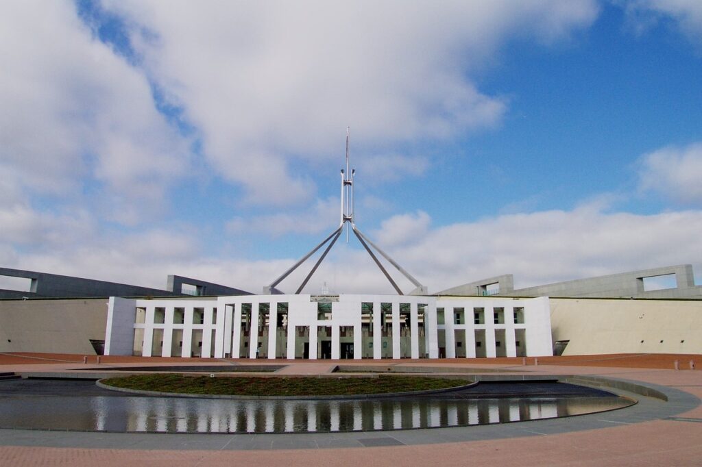 Australia's Parliament House, a white building with lots of long windows, standing in front of a small lake.