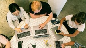Aerial view of diverse group of people working on laptops around a table.